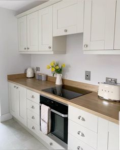 a kitchen with white cabinets and wooden counter tops, including a black stove top oven