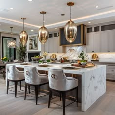 a large kitchen with marble counter tops and gold pendant lights