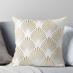 a white and gold throw pillow sitting on top of a gray couch next to pillows