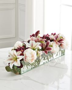 a glass vase filled with flowers on top of a white marble table next to a window