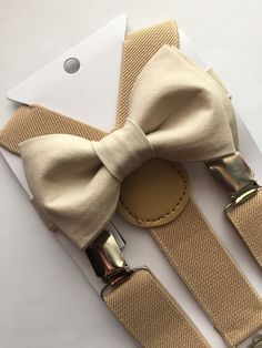 "Adorable taupe bow tie, made with 100% cotton.  Size 6m-2yo: adjustable elastic  suspenders run from 16\"- 25\" long, bow tie's neck strap is about 14\" long; (adjustable), velcro closure Size 3yo-5yo: adjustable elastic suspenders run from 16\"-25\" long, bow tie's neck strap is about 15\" long; (adjustable), velcro closure Size 6yo-12yo: adjustable elastic suspenders run from 21\"-34\" long, bow tie's neck strap is about 16 1/2\" long; (adjustable), velcro closure Size adult up to 5'6\": adju Champagne Chambelan Suits, Brown Chambelan Suits, Champagne Dama Dresses, Chambelanes Outfits Quinceanera, Chambelan Outfits, Red Quince Theme, Tan Bow Tie, Chambelanes Outfits, Champagne Bow Tie