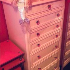 a white dresser sitting next to a pink wall