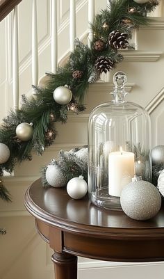 christmas decorations and candles on a table in front of the banister with pine cones