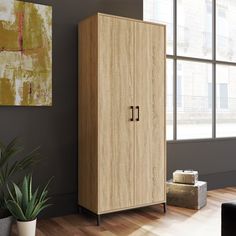 a large wooden cabinet next to a plant in a living room with wood flooring