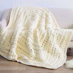 a white crocheted blanket sitting on top of a chair