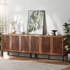 a wooden sideboard sitting on top of a hard wood floor next to potted plants