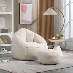 a white chair and ottoman in a living room with a lamp on the side table