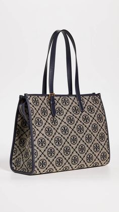 The T Monogram Jacquard Tote instantly elevates any outfit with charm and sophistication. This striking bag features a monogram jacquard print adorned with leather trim for lasting quality. Zip closure and interior pockets keep essentials organized, while sturdy construction and suede lining promise dependability. As versatile as your favorite Instagram posts, carry it everywhere as the perfect accent. Handcrafted details and ethical production make this a bag to treasure. Monogram Print Top Handle Shoulder Bag For Daily Use, Tan Monogram Canvas Shoulder Bag, Daily Use Top Handle Shoulder Bag With Monogram Print, Timeless Monogram Canvas Shoulder Bag For Travel, Timeless Monogram Canvas Bag For Everyday Use, Daily Use Monogram Print Top Handle Shoulder Bag, Tan Bags With Leather Trim And Monogram Canvas, Tan Monogram Canvas Bag With Leather Trim, Tan Monogram Canvas Bags With Leather Trim