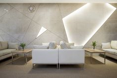 a living room filled with white couches next to a wall covered in geometric shapes