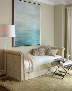 a living room filled with furniture and a painting hanging on the wall above it's headboard