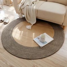 a living room with a couch, coffee cup and blanket on the floor in front of it