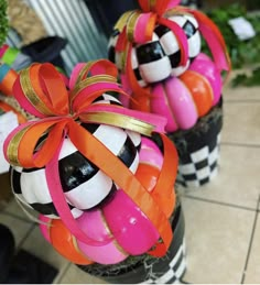 two vases decorated with soccer balls and ribbon tied around the top one is black, white, and pink