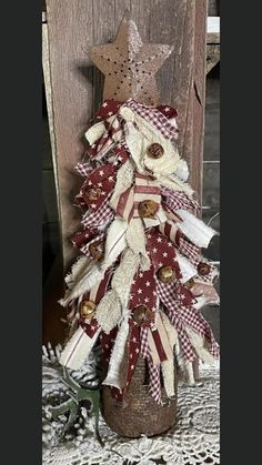 a christmas tree made out of old fabric and other items is displayed in front of a wooden door