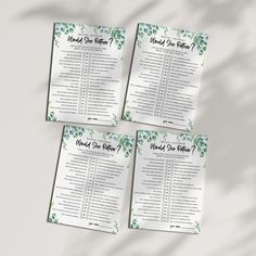 four wedding seating cards with green leaves and flowers on the front, one for each seat