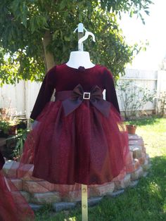 "This is a beautiful, New, Upcycled dress. New dress with Tags! Pictures do not do any justice to this gorgeous dress. This dress comes in a beautiful shade of Burgundy, also available in True Red. The top is Velvet and has a very pretty handmade fabric flower on the round neckline, has long sleeves, and a beautiful taffeta bow with a rhinestone buckle. The top of the skirt is a gorgeous glitter tulle with some hints of red. Dress has a built in crinoline. Please see all pictures!! FOR RED: www. Velvet And Tulle Dress, Glitter Tulle Dress, Christmas Gown, Dress Glitter, Thanksgiving Dress, Upcycled Dress, Girls Thanksgiving, Christmas Dresses, Girls Holiday