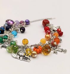 "- Autumn Charm Bracelet Stainless Steel Chain is adjustable from 6.5\" - 9\" with a lobster claw closure and extension chain The bracelet links are filled with a rainbow of glass and gem stone beads and crystals - really pretty. Mixed between the beads and gemstones are autumn themed silver and enamel charms. This is a great gift for anyone who loves the quirky symbols and bright colors of fall. I make these as they are ordered, so the processing time is 4 days. Your bracelet will be carefully