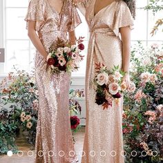 two women standing next to each other in front of flowers and greenery wearing gold dresses