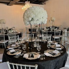 a black table topped with lots of white flowers and place settings for an elegant dinner