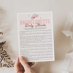 someone holding up a printable bachelor party minds card on top of a white table