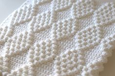 a white crocheted blanket laying on top of a table