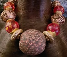 The huge focal bead on this tribal beaded statement necklace is ancient and from Java/Indonesia. It measures 2" x 2" or 50 mm by 50 mm and features a red, blue and white pattern in the shapes of "eyes." These beads are very rare and scarce, but to find a pristine one in this size is almost unheard of. The other beads include Tibetan copper repousse, Tibetan "Amber" (actually plastic or resin), unique gold tone metal disks, burnished gold tone contemporary wavy spacers, red magnesite rounds and ornate vintage brass beads. Non-adjustable 20" with a copper hook and eye closure. If requested, I can add an extender chain free of charge. If you research the focal bead you can verify the rarity and scarcity which is reflected in the price point. Would make a great gift for a collector of ancient Shapes Of Eyes, Evil Eyes, Brass Beads, Statement Choker, Statement Art, February 3, Beaded Statement Necklace, Red Eyes, Eye Shapes