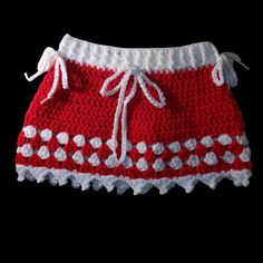 a red and white crocheted skirt with hearts on the bottom, attached to a black background