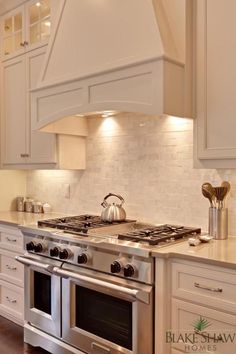 a stove top oven sitting inside of a kitchen next to white cabinets and counter tops