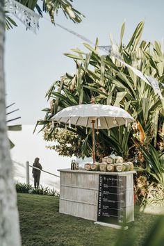 an umbrella is set up on the side of a small bar with drinks under it