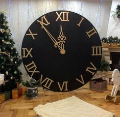 a large black clock sitting on the floor in front of a christmas tree and fireplace