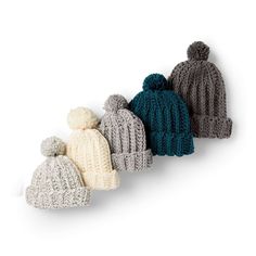 three knitted hats with pom poms on them are lined up in different colors