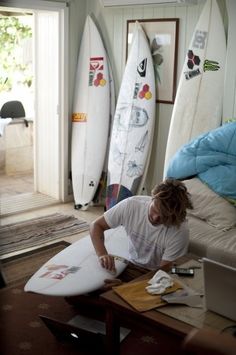 a man sitting on top of a couch next to surfboards in a living room