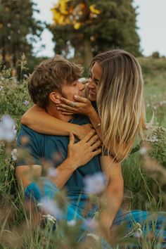 two people sitting in the grass hugging each other