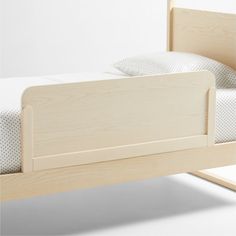 a wooden bed frame with white sheets and pillows