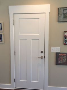 a white door in a room with pictures on the wall