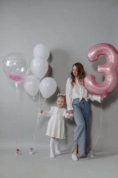 a mother and daughter holding balloons in front of the number three