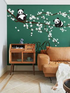 a living room with green walls and pandas on the tree branch wall decals