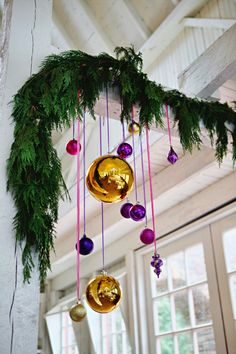 christmas decorations hanging from the ceiling with pine branches and ornaments on it's side