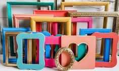 there are many different colored frames on the table and one is shaped like a heart