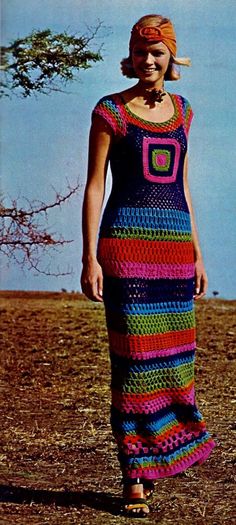 a woman in a colorful crocheted dress standing on the ground