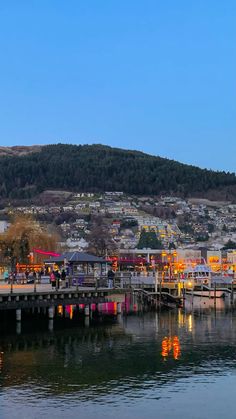 there are many boats docked at the pier in the harbor with mountains in the background