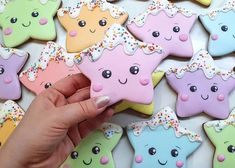 a hand is holding some decorated cookies in the shape of stars with sprinkles on them