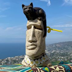 a cat sitting on the head of a statue