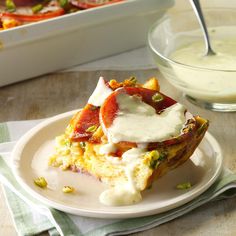 a slice of pizza on a white plate with sour cream and tomatoes in the background