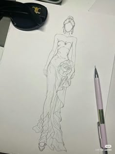 a drawing of a woman's dress on paper next to a pair of scissors