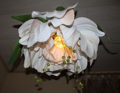 a white flower hanging from the ceiling with green beads on it's center piece