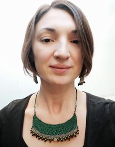 a woman wearing a green beaded necklace and earrings