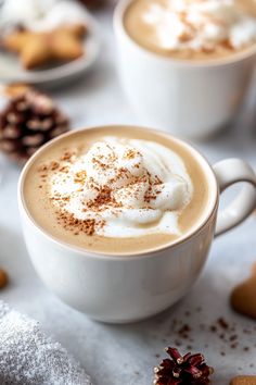 Two cups of frothy coffee topped with whipped cream and cinnamon, surrounded by holiday decor. Christmas Coffee Recipe, Starbucks Recipes Hot Drinks, Gingerbread Oatmilk Chai Latte Starbucks, Gingerbread Chia Latte, Soft Gingerbread Latte Cookies, Iced Gingerbread Chai Latte, Christmas Coffee Drinks, Vanilla Gingerbread Latte, Gingerbread Latte Syrup