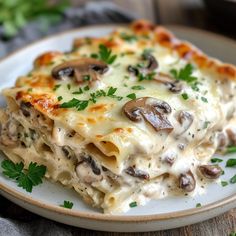 a white plate topped with lasagna covered in mushrooms and cheese on top of a wooden table