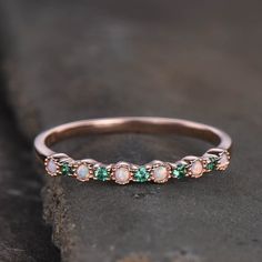 a rose cut diamond and emerald band ring on a stone surface with the stones in between