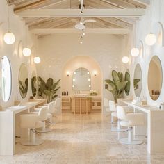 the interior of a hair salon with white chairs and large mirrors on the wall above them